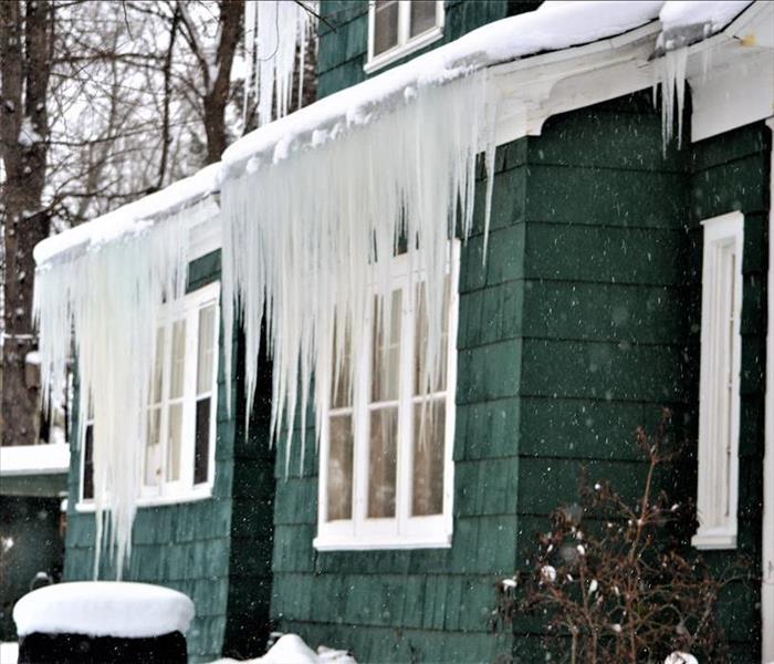 Green house with large icicles hanging from the gutters. 